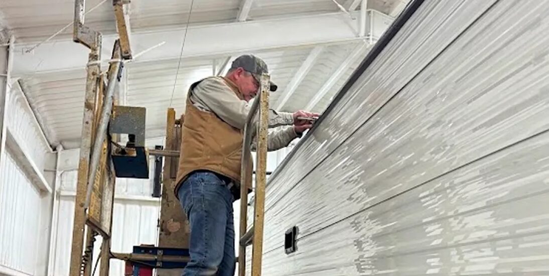 Applicator working along the side of a travel trailer in the shop