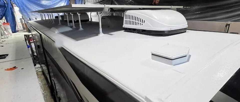 Long RV roof finished in white polyurea inside a coating shop