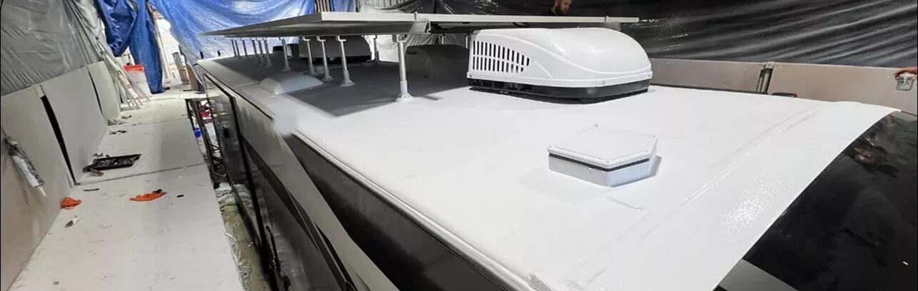 Long RV roof finished in white polyurea inside a coating shop